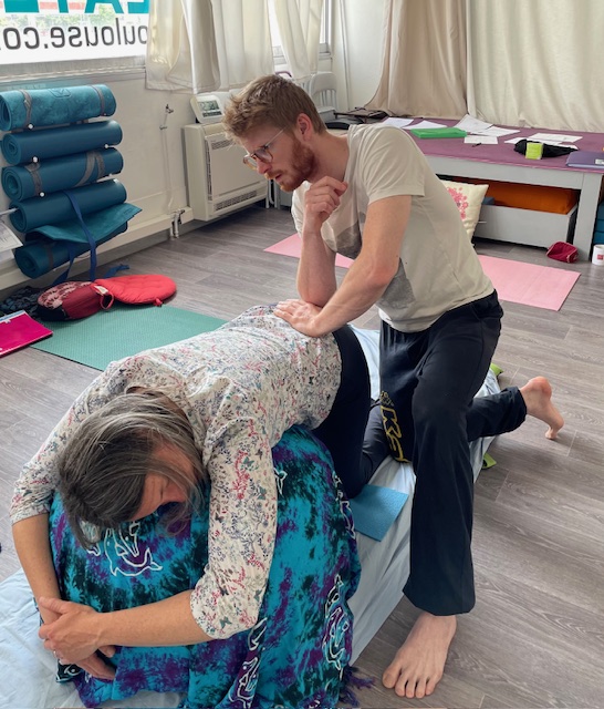 Cyril donnant un shiatsu à une femme sur un ballon, permettant à une femme enceinte d'être plus à son aise